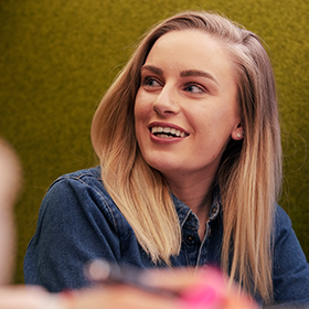 Blonde student sat in a booth at the library, laughing.