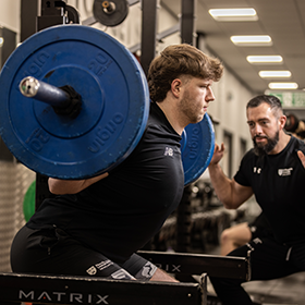 Student-athlete being coached through weight training.