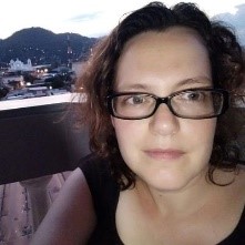 a woman wearing glasses and smiling at the camera