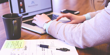 a person sitting at a table using a laptop