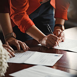 Photo of a person signing documents on a table