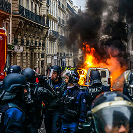 Image of riot police with fire in the background
