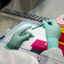 Close up of a lab technician pipetting a substance into a tube