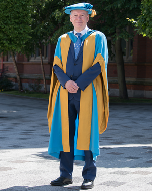 Professor Andrew Wathey standing on Northumbria University's City Campus in academic dress, before receiving his Honorary Degree