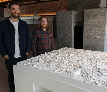Caption: James Charlton (L) and Adam Cosheril (R) stood with the model at its new location in Newcastle Civic Centre
