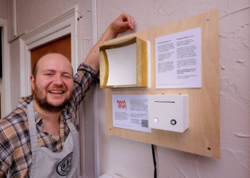 Caption:Café Owner Tommy with the new installation at Rochester Relish
