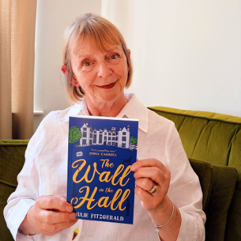 caption:Author Julie Fitzgerald pictured holding her book The Wall in the Hall