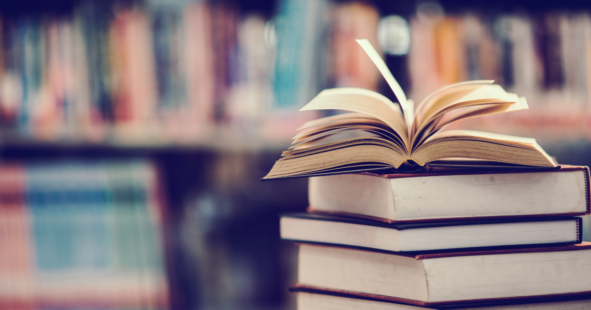 an image showing a pile of books with one open on top