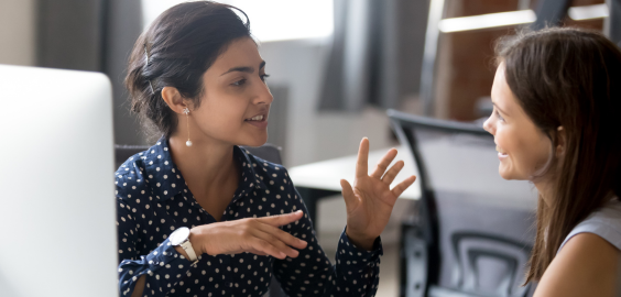 Two women chatting by a computer