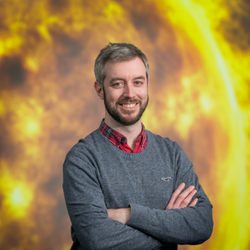 a headshot image of Andy Smith smiling at the camera with an image of the sun in the background
