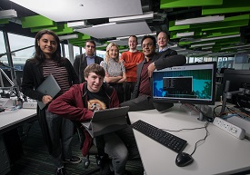 a group of people standing in front of a computer