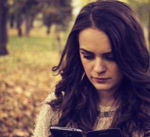 Woman looking at phone with sad look on her face