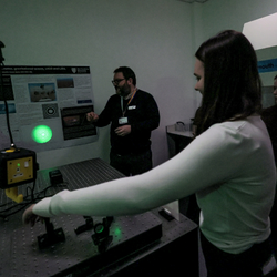 A student is pictured carrying out an experiment, shining a green laser at a wall