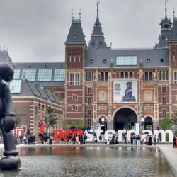 a castle like building with people in the street with Rijksmuseum in the background