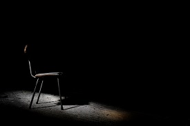 image shows a single chair in a dark room
