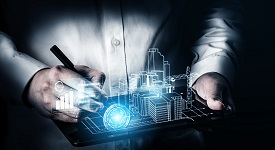 Stock image depicting digital construction. A person holds a tablet device with a hologram of a building being beamed out of it.