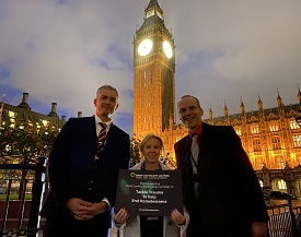 pictured left to right is David Smith, CEO of the charity Oasis Community Housing, and Dr Adele Irving and Dr Jamie Harding of Northumbria University, standing in front of the Houses of Parliament holding the report on homelessness and trauma which has just been published