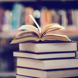 an image showing a pile of books with one open on top