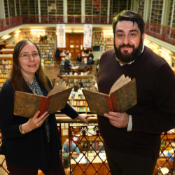 Pictured are Dr Katherine Butler of Northumbria University and James Smith of the Lit & Phil standing holding a book each with rows of books in the background