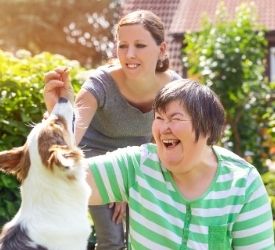 Woman with learning disability and her carer playing with a dog