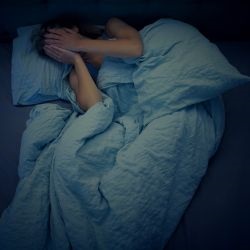 a woman struggling to sleep in bed