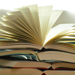 a pile on books with the top one open and fanned out