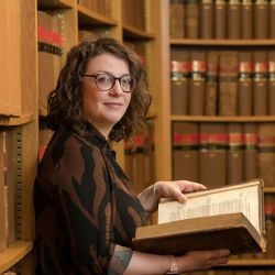 academic Jennifer Aston pictured in a law library holding an open book