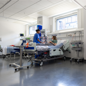 Caption:Stock image of a women in a hospital bed being visited by a healthcare professional