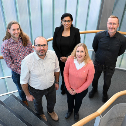 a group of five people pictured standing on a staircase