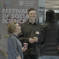 two people chatting in from of a banner that reads 'festival of social sciences'