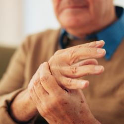 an image of an elderly man holding and massaging his hand as if in pain