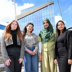 four women standing with a building behind them