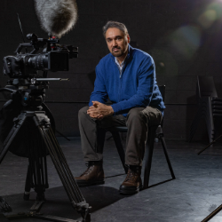 Rehan Malik sitting in a theatre next to camera equipment