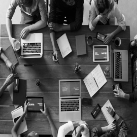 Black and white image of people around a table working