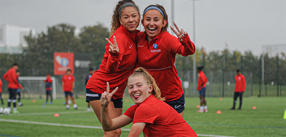 i2i women's team laughing and joking during training at Coach Lane Campus in the rain.