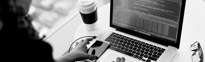 Working at laptop with coffee cup, smart phone and glasses