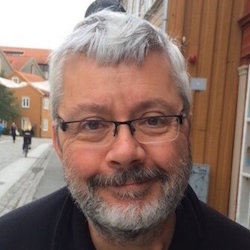 a man wearing glasses and smiling at the camera