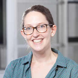 a woman wearing glasses and smiling at the camera