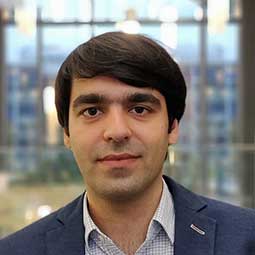 a man wearing a suit and tie smiling at the camera