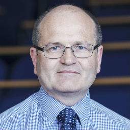 a man wearing glasses and smiling at the camera