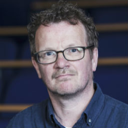 a man wearing glasses and smiling at the camera