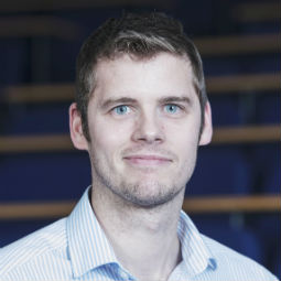 a man wearing glasses and smiling at the camera