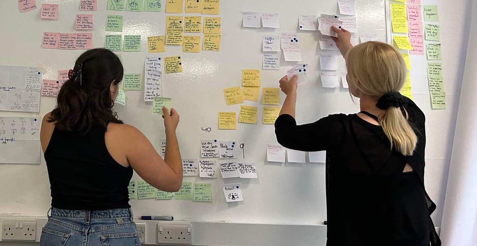 Two girls putting post it notes on a wall