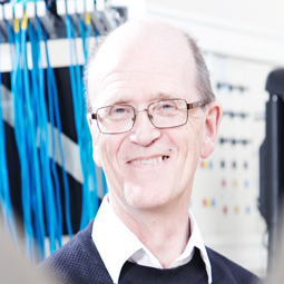 a man wearing a suit and tie smiling at the camera