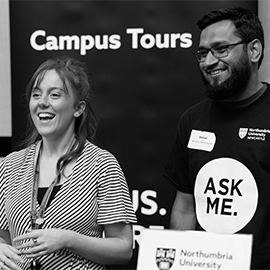 Two students, one male, one female, standing in front of a black banner that reads "Campus Tours"