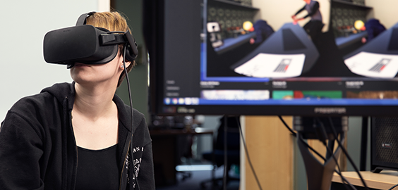 Person using a VR headset with a connected screen displaying virtual reality content.