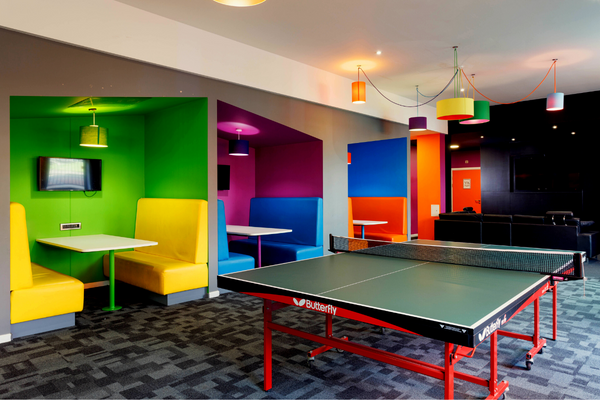 Brightly decorated social space with booths and table tennis table.