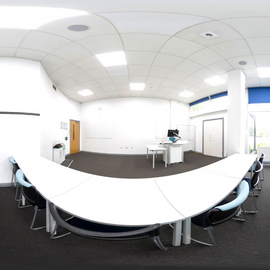 Fisheye image of a flat classroom with projector screen and PC. 