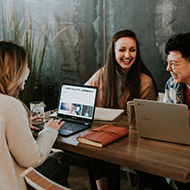 a group of people sitting at a table with a laptop