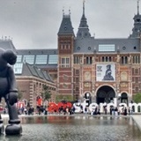 a group of people walking in front of Rijksmuseum
